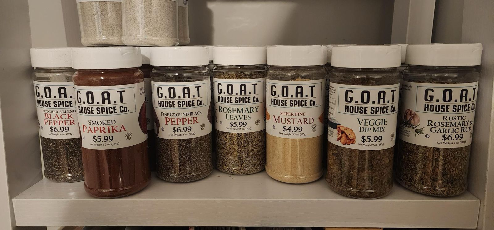 A shelf of G.O.A.T House Spice Co. shaker jars